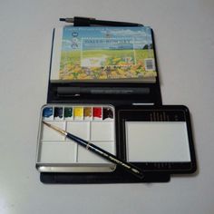 an artist's kit with watercolor paints and a brush