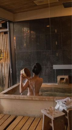 a woman is sitting in the bathtub while holding a hat