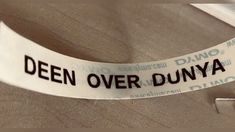 a close up of a white ribbon with black writing on it that says,'deen over dunya '