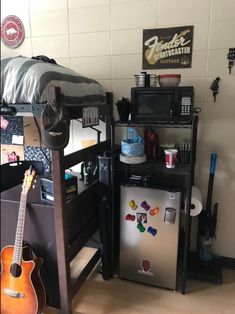 a room with a bed, refrigerator and guitar