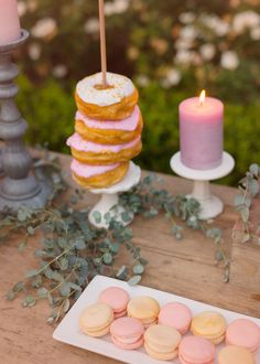 a table topped with pink and yellow macaroons next to a tall candle holder