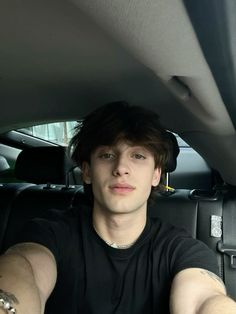 a young man sitting in the back seat of a car