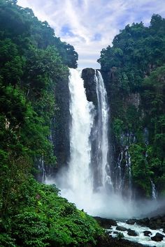 a large waterfall surrounded by lush green trees