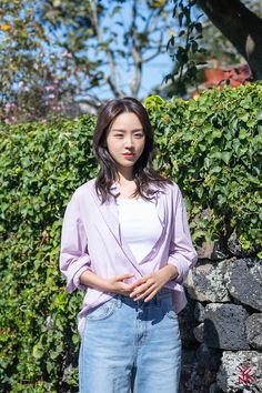 a woman standing in front of a stone wall with her hands on her hips and looking at the camera