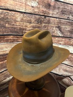 Vintage American Hat Company Cowboy Hat (Circa 1960s-1970s) Step back in time with this authentic vintage cowboy hat from the renowned American Hat Company. This hat, likely dating from the 1960s to 1970s, embodies the spirit of the American West and has been crafted with the quality and durability the brand is famous for. **Key Features - **Brand American Hat Company - **Era Estimated 1960s-1970s - **Material High-quality felt, showing a rich patina - **Color Classic brown, with a dark band - **Condition This hat has been well-loved and worn, showcasing a genuine vintage aesthetic. It features signs of wear consistent with its age, adding to its authentic charm. The interior band and lining are intact, though they do show some wear. - **Size 7 1/4  **Description This hat is not just an ac American Hat Company, Vintage Cowboy Hat, American Hat, Patina Color, Vintage Cowboy, Classic Brown, American West, Step Back, Cowboy Hat