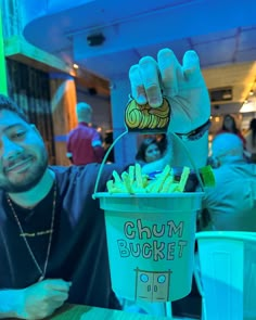 a man sitting at a table with a bucket full of food in front of him