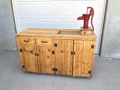 a wooden cabinet with a red faucet sitting on top of it next to a garage door