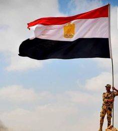 a man holding a flag on top of a hill