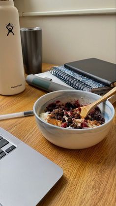 a bowl of oatmeal is sitting on a desk next to a laptop