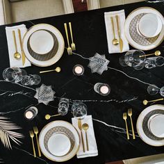 the table is set with gold and white plates, silverware, and napkins