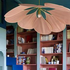 a room filled with lots of books and shelves covered in pink paper flowers hanging from the ceiling