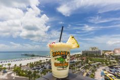 a drink sitting on top of a table next to the ocean