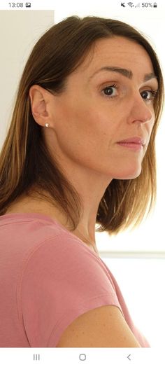 a woman looking at the camera while wearing a pink shirt