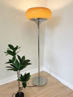 a floor lamp next to a potted plant in a corner with a white wall