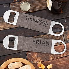 two personalized bottle openers sitting on top of a wooden table next to nuts