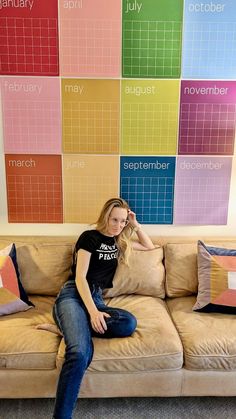 a woman sitting on top of a couch in front of a wall with calendars