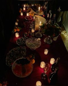 a long table with candles, fruit and wine on it is set up for a party