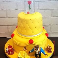 a yellow cake decorated with beauty and the beast figures