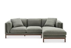 a gray sectional couch with pillows on the back and armrests, in front of a white background