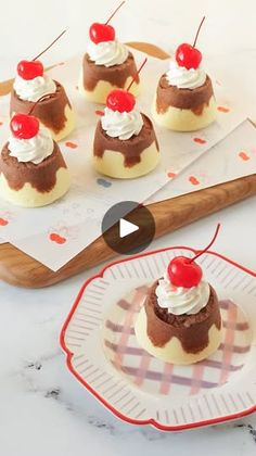 mini desserts with whipped cream and cherries on a plate next to a cutting board