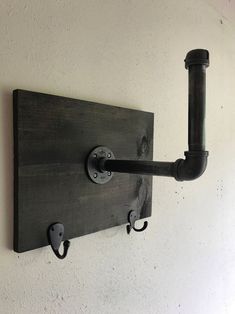 a wall mounted pipe holder on the side of a white wall with two black pipes attached to it