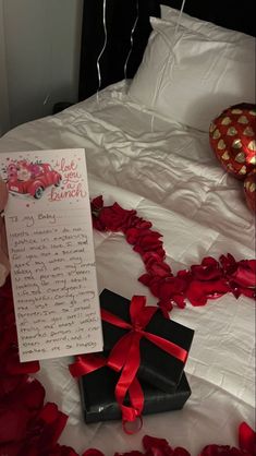 a bed with red rose petals on it and a note that says i love you so much