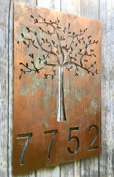 a metal house number sign with a tree on it's front and the number twenty seven