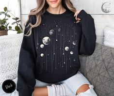 Add a cosmic touch to your wardrobe with our Moon Galaxy Boho Sweatshirt. Featuring a detailed moon phase design set against a galaxy backdrop, this sweater is perfect for astrology lovers. Its vintage style offers both comfort and a classic look, making it a versatile addition to your collection. 🌕🌌  Here's what you need to know  ★ Fit ★ This is a unisex Sweatshirt. It might be a bit larger than your usual size. So, check out our size chart to find your perfect fit. Want an oversized look? Pick one or two sizes larger than you normally would. ★ Fabric ★ We're all about comfort and quality. ●  50% cotton, 50% polyester ●  Pre-shrunk ●  Classic fit ●  1x1 athletic rib knit collar with spandex ●  Air-jet spun yarn with a soft feel and reduced pilling ●  Double-needle stitched collar, shoul Spacecore Outfits, Galaxy Backdrop, Moon Galaxy, Boho Sweatshirt, Vintage Sweater, Design Set, Moon Phases, Air Jet, Pick One