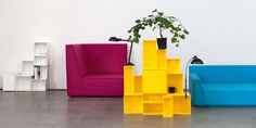 three different colored chairs sitting next to each other in front of a white wall with a potted plant on top