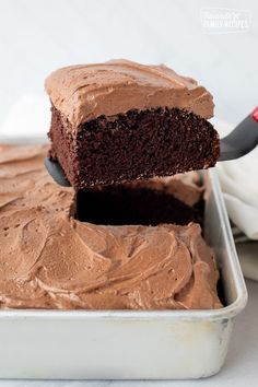 a piece of chocolate cake being lifted from a pan with the rest of the cake in it