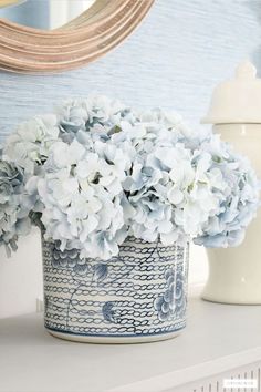 a blue and white flower pot sitting on top of a table next to a mirror