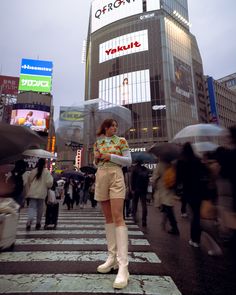 a woman standing in the middle of a crosswalk holding an umbrella