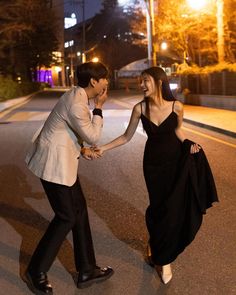 a man and woman dancing on the street at night