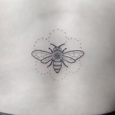 a small bee tattoo on the back of a woman's rib - up stomach