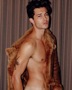 a shirtless man with no shirt standing in front of a curtain and wearing a fur coat