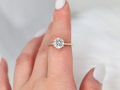 a woman's hand with a diamond ring on top of her finger, showing the center stone