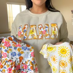 a woman is holding three baby ones in her hands and the word mama spelled out with letters on them