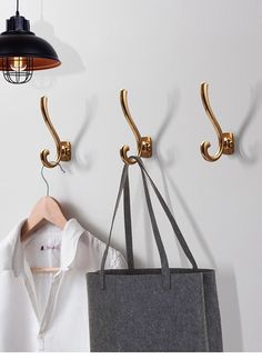 three hooks are hanging on the wall next to a bag and a shirt hanger