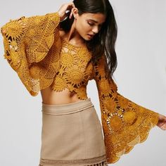 a woman wearing a brown skirt and yellow top with crochet lace on it