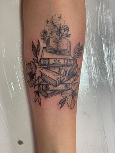 a tattoo with books and flowers on it