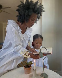 a woman and child are sitting at a table with a candle in front of them