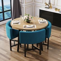 a dining room table with blue chairs and white plates on the wooden table, in front of a large window