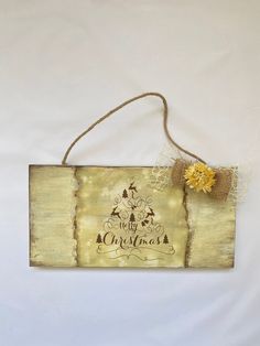 a wooden sign that says merry christmas with a yellow flower hanging from it's side