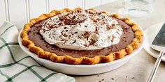 a pie with whipped cream and chocolate toppings in a white bowl on a table