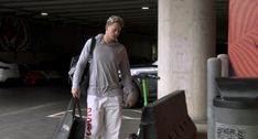 a man walking down the street with luggage in his hand and two suitcases behind him