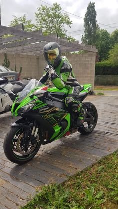 a man riding on the back of a green motorcycle