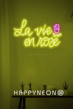 a neon sign that says la vie en rose on the wall above a table with candles