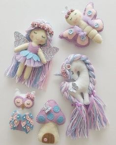 several small stuffed animals are arranged on a white surface, including one unicorn and the other an owl