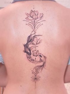 a woman's back with a fish and flower tattoo on it