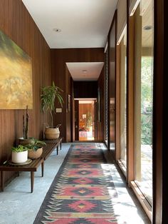 the hallway is lined with wooden paneling and potted plants